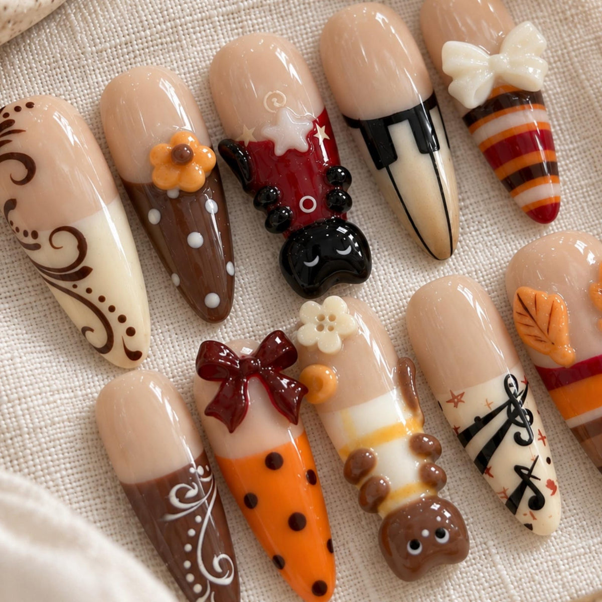 A set of ten almond-shaped press-on nails featuring a nude base with various decorative elements including brown swirls, orange polka dots, a 3D ladybug, a 3D bee, a white bow, a brown bow, piano keys, musical notes, and autumn leaves.