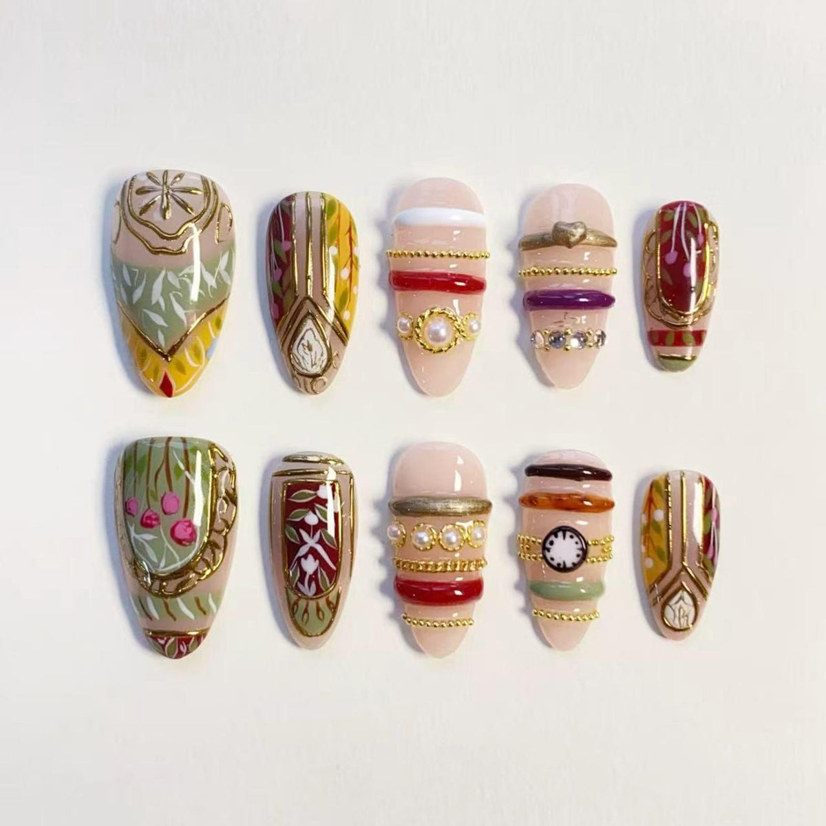 A set of ten almond-shaped press-on nails featuring intricate designs. The nails display a variety of patterns including floral motifs, gold metallic accents, horizontal stripes, small pearls, and a miniature clock face illustration.