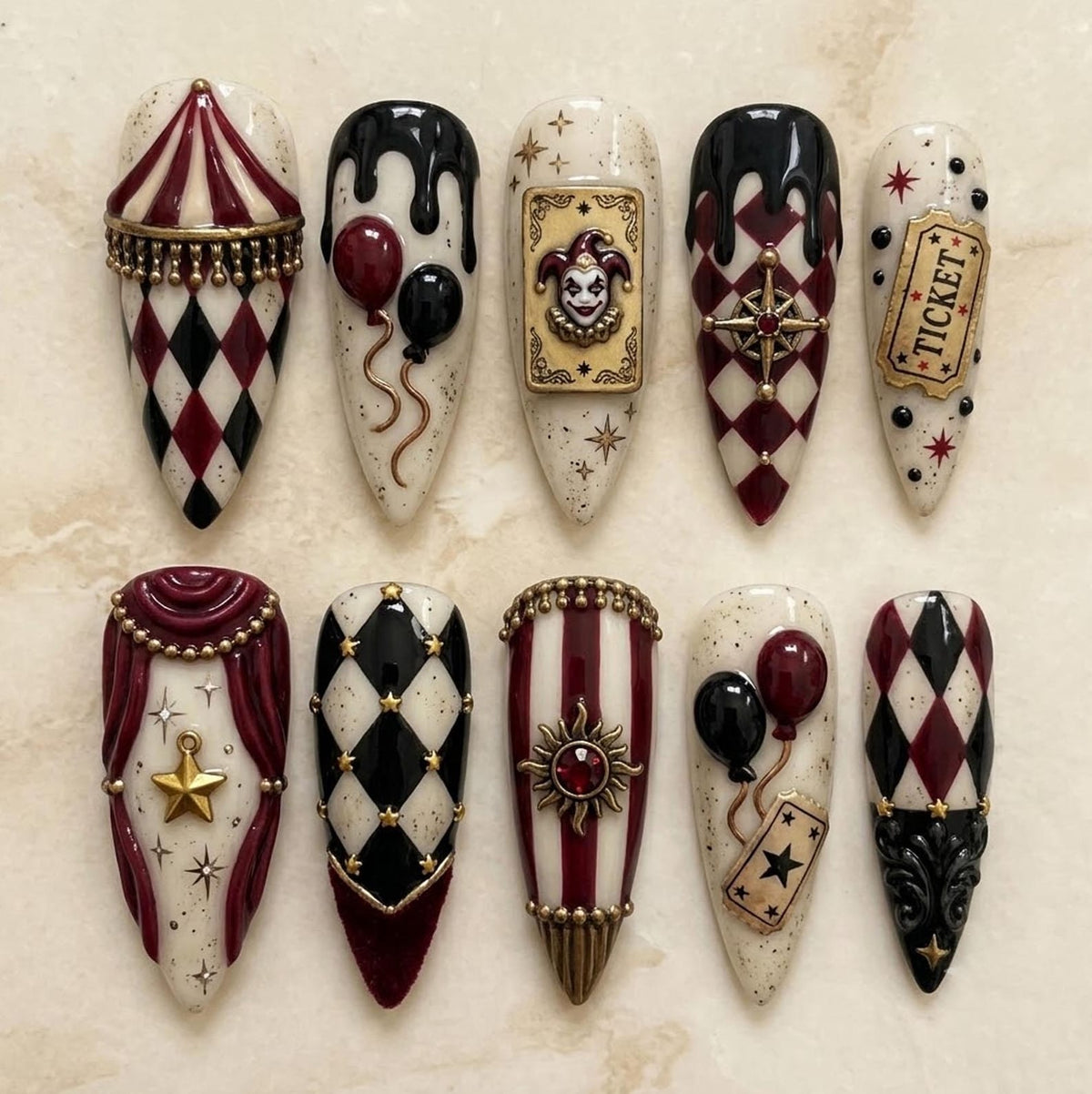 A set of ten almond-shaped press-on nails featuring a circus theme with a color palette of cream, burgundy, and black. Designs include harlequin patterns, a jester card, balloons, a ticket, a sun charm, and gold star accents.