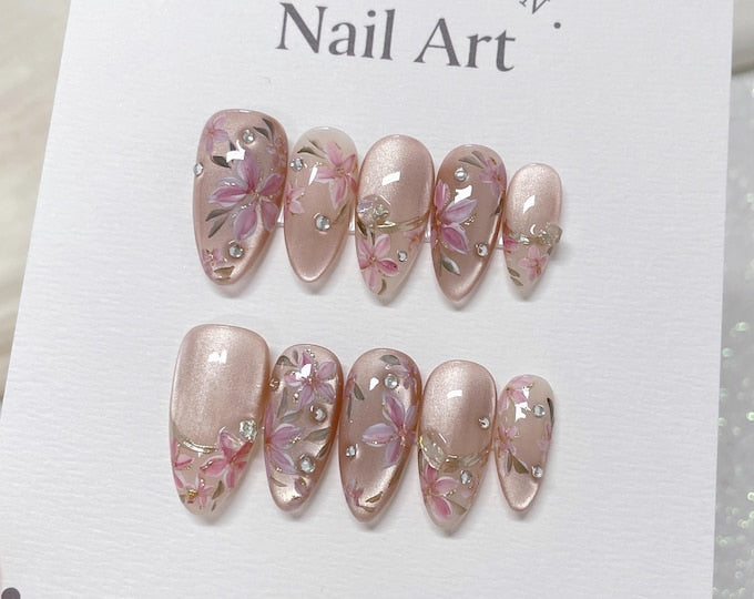 A set of ten pink and white nail tips with floral designs and rhinestones. The nail tips are displayed on a white card with the text "COLLECTION. Nail Art."