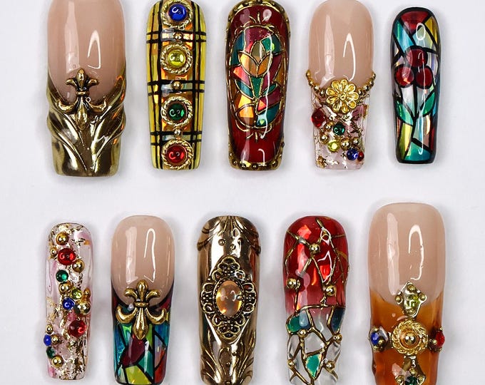 Ten decorative fake nails with a stained glass design. The nails are decorated with gold accents, rhinestones, and other embellishments.